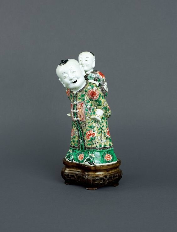 Chinese famille verte biscuit porcelain ‘piggyback’ group, Early Kangxi period, circa 1680